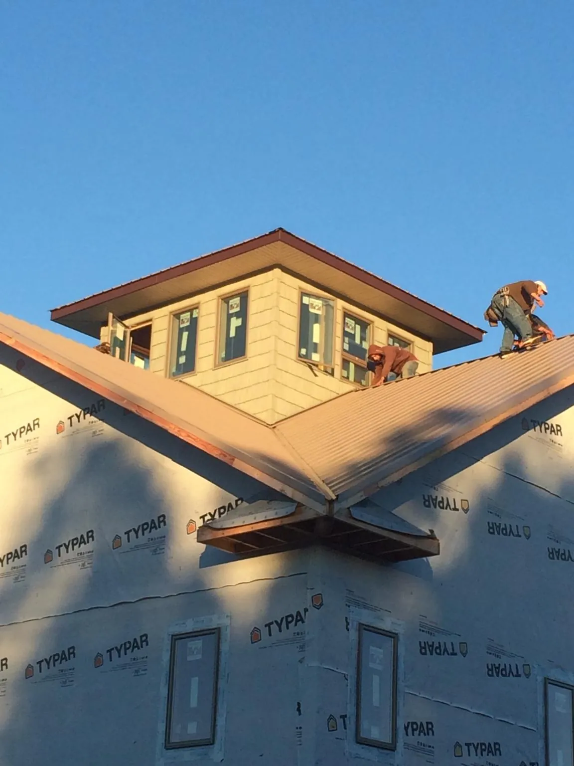 Roofers working around a rooftop cupola on a new metal roof at sunset — Roof Waterproofing in Bainbridge by Roofing Brothers